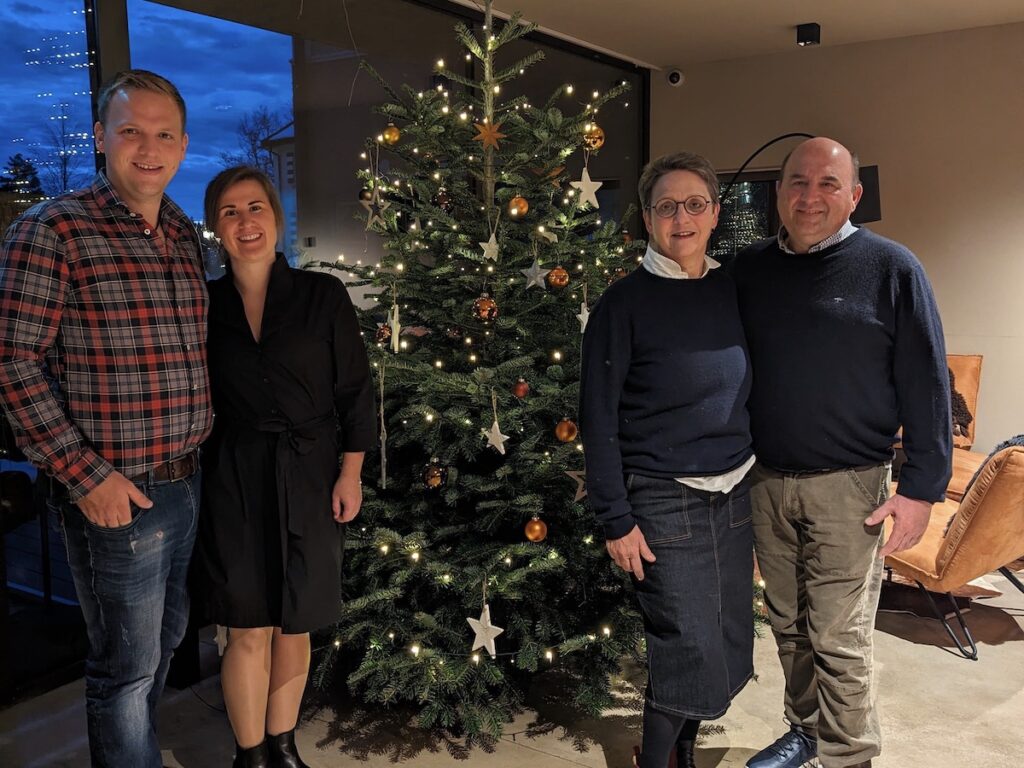 Eine Familie steht vor einem Weihnachtsbaum